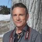 A photo of handsome siteLease client Darren Colten smiling outdoors with a camera around his neck